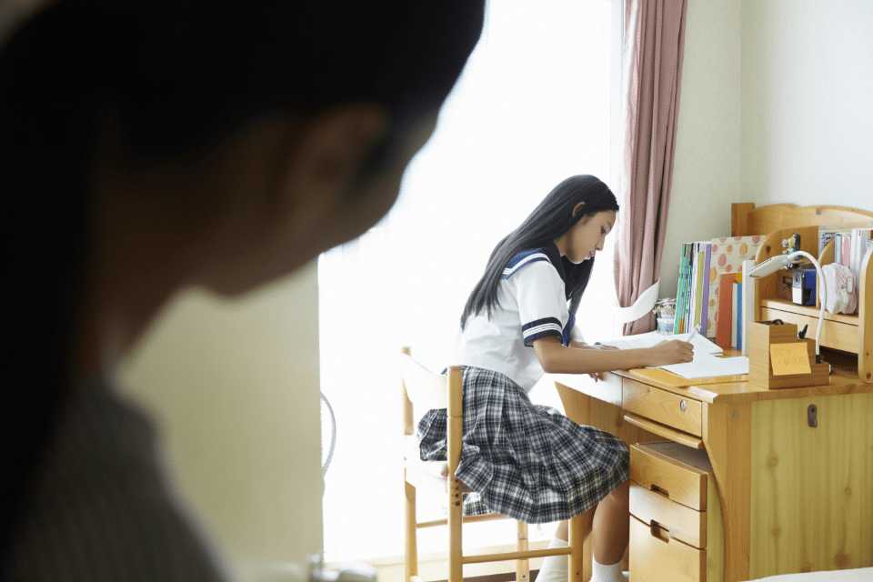 自宅で勉強する中学生と見守る保護者