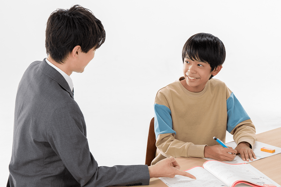 個別指導塾で勉強する講師と男子生徒